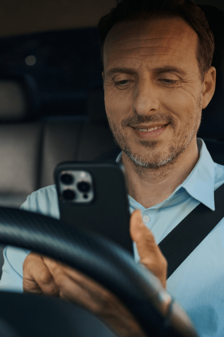 Driver in a Freenow taxi, looking at his phone