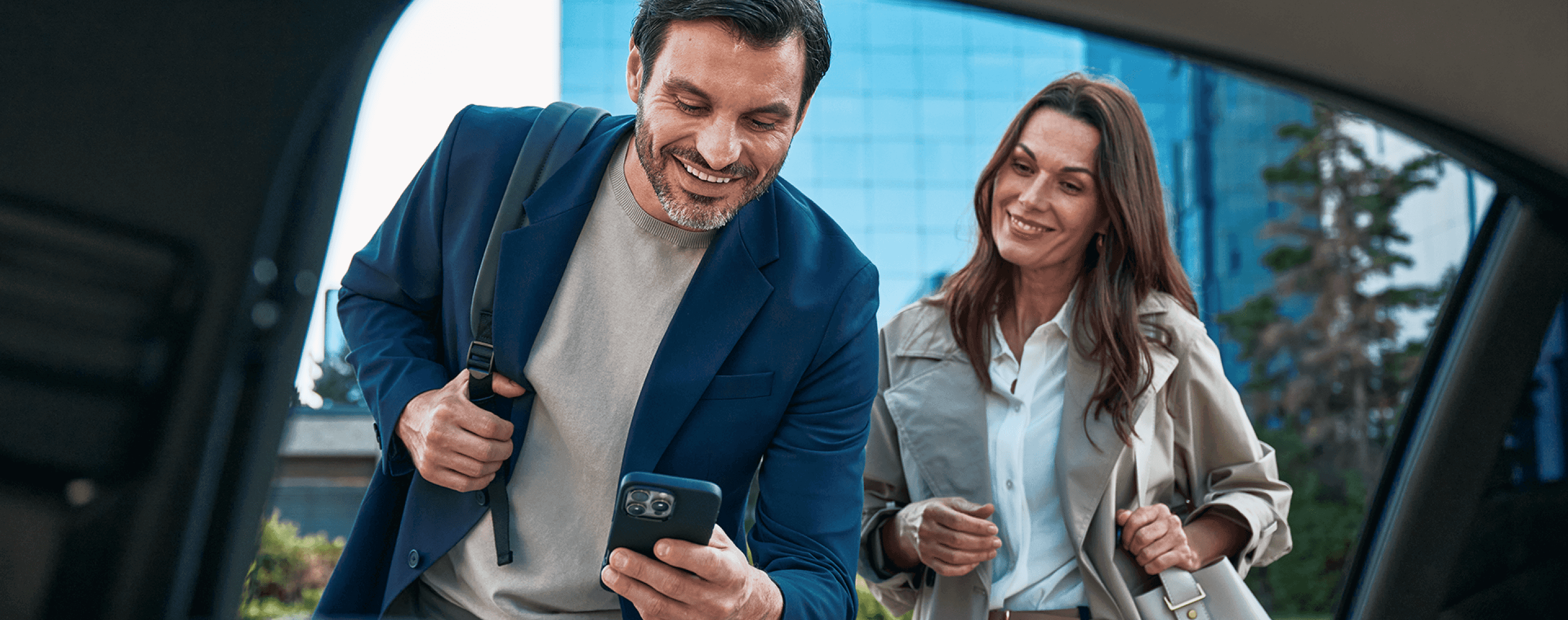 A business traveller sitting in a Freenow taxi showing iPad to colleague.